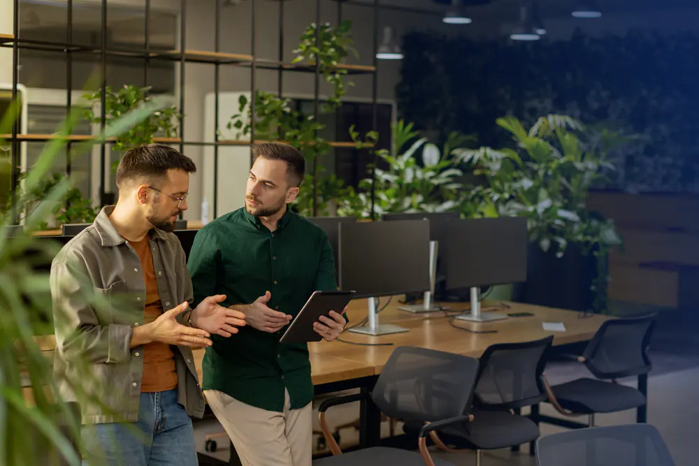 Zwei Männer mit Tablet in der Hand sind am reden in einem modernen Büro